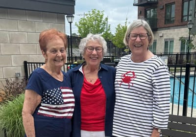 Three residents smiling together outdoors