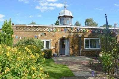 Exterior view of a building with garden and bunting.