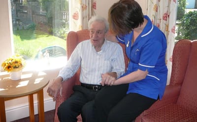 Staff member assisting a resident in a cozy lounge.