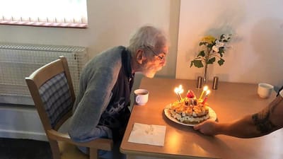 Elderly man celebrating a birthday with cake.