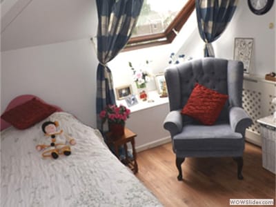 Cozy bedroom with a chair and decorative elements.