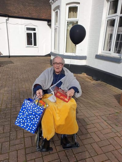 Resident celebrating outdoors with gifts and a balloon.