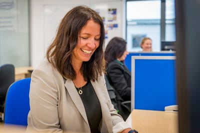 Woman smiling at her desk in an office setting.
