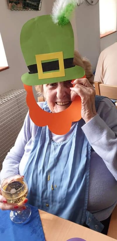 Elderly woman smiling with festive accessories.