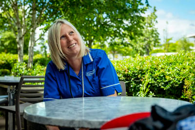 Staff member smiling outdoors in a garden area