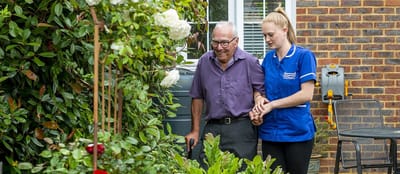 Staff assisting a resident in a garden