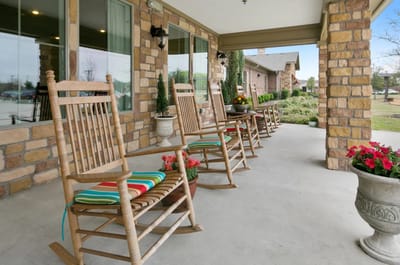Outdoor seating area with rocking chairs and flowers.