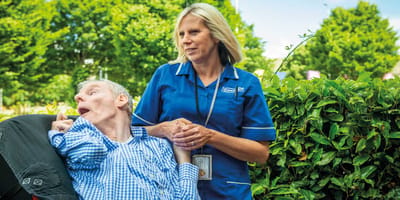 Care staff assisting a resident outdoors.