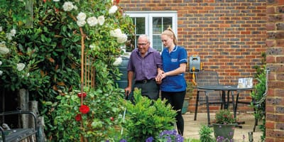 Staff assisting a resident in a garden