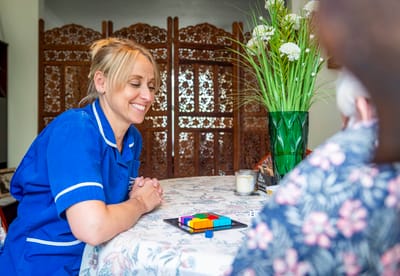 Staff interacting with a resident at a table.