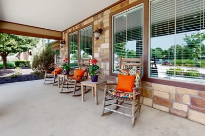 Outdoor seating area with rocking chairs and plants.