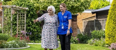 Resident and staff walking in a garden