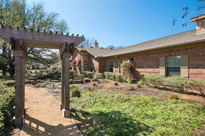 Garden area with a pergola and brick building.