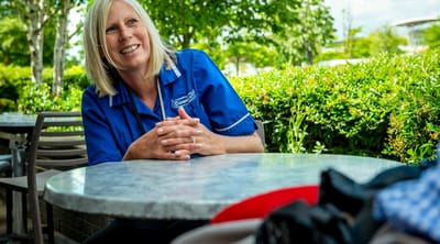 Staff member smiling outdoors at a table.