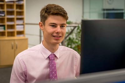 Young man in a professional setting at a computer.