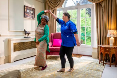 Two women dancing in a bright common area.