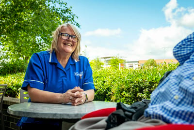 Staff member smiling outdoors with a resident