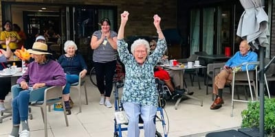Residents celebrating outdoors with raised hands.