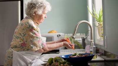 Senior woman washing vegetables in a kitchen