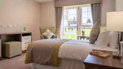 A cozy resident room with a bed and chair.