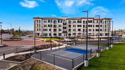 Exterior view of a senior living facility with tennis courts