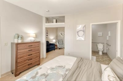 A well-decorated resident room with a bed and sitting area.