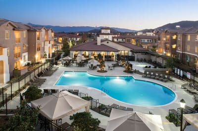 Outdoor pool area with seating and buildings in the background