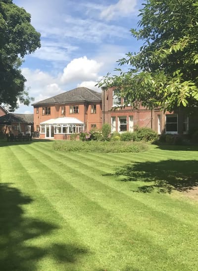 Well-maintained lawn with brick building in background