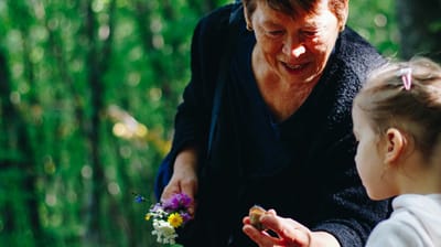 An older woman engaging with a young girl outdoors.