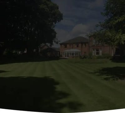 Grass lawn with building and trees in background.