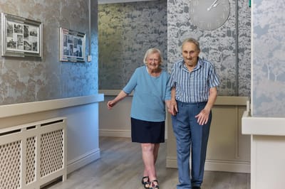 Two residents walking together in a corridor.