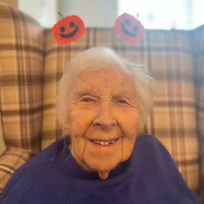Smiling elderly woman with festive decorations.