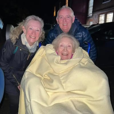 Three people smiling outside at night