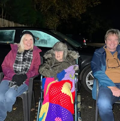 Three people sitting outdoors at night.