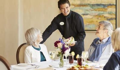 Table service with residents enjoying meals together.