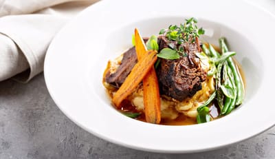 A plated meal with beef, carrots, and green beans.