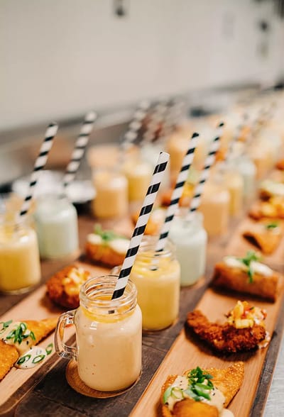 Colorful drinks and appetizers on wooden platter.