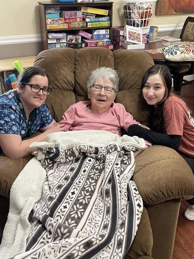 Staff and resident smiling together in a cozy common area