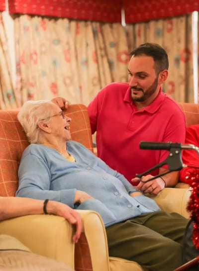 Resident laughing with staff member in a cozy lounge