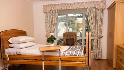 Cozy resident room with a hospital bed and armchair