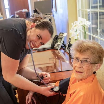 Staff member taking a resident's blood pressure in the facility