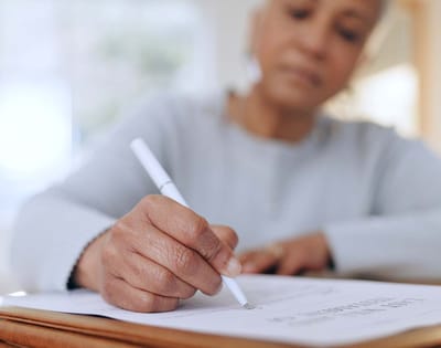 Senior woman writing on paper in a well-lit space