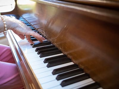 A resident playing the piano with a focus on hands