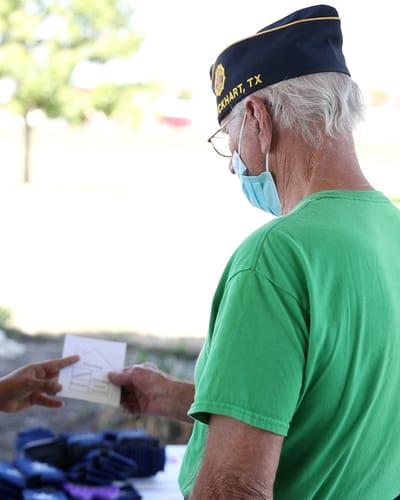 An elderly man interacting outdoors while wearing a mask