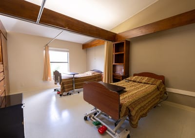 Resident room with two beds and a dresser