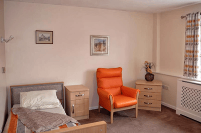 Cozy resident room with an orange chair and artwork