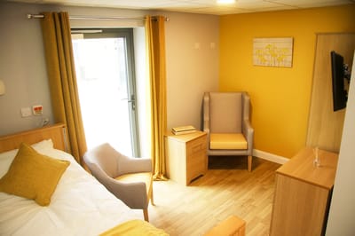 A cozy private resident room with yellow accents