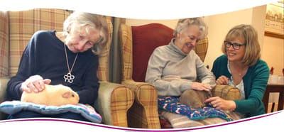 Residents interacting with guinea pigs in a cozy lounge