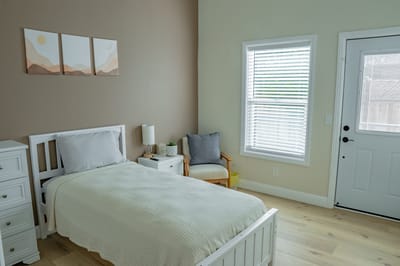 Bright private resident room with a bed and chair