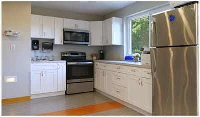 Bright kitchen area with white cabinets and modern appliances